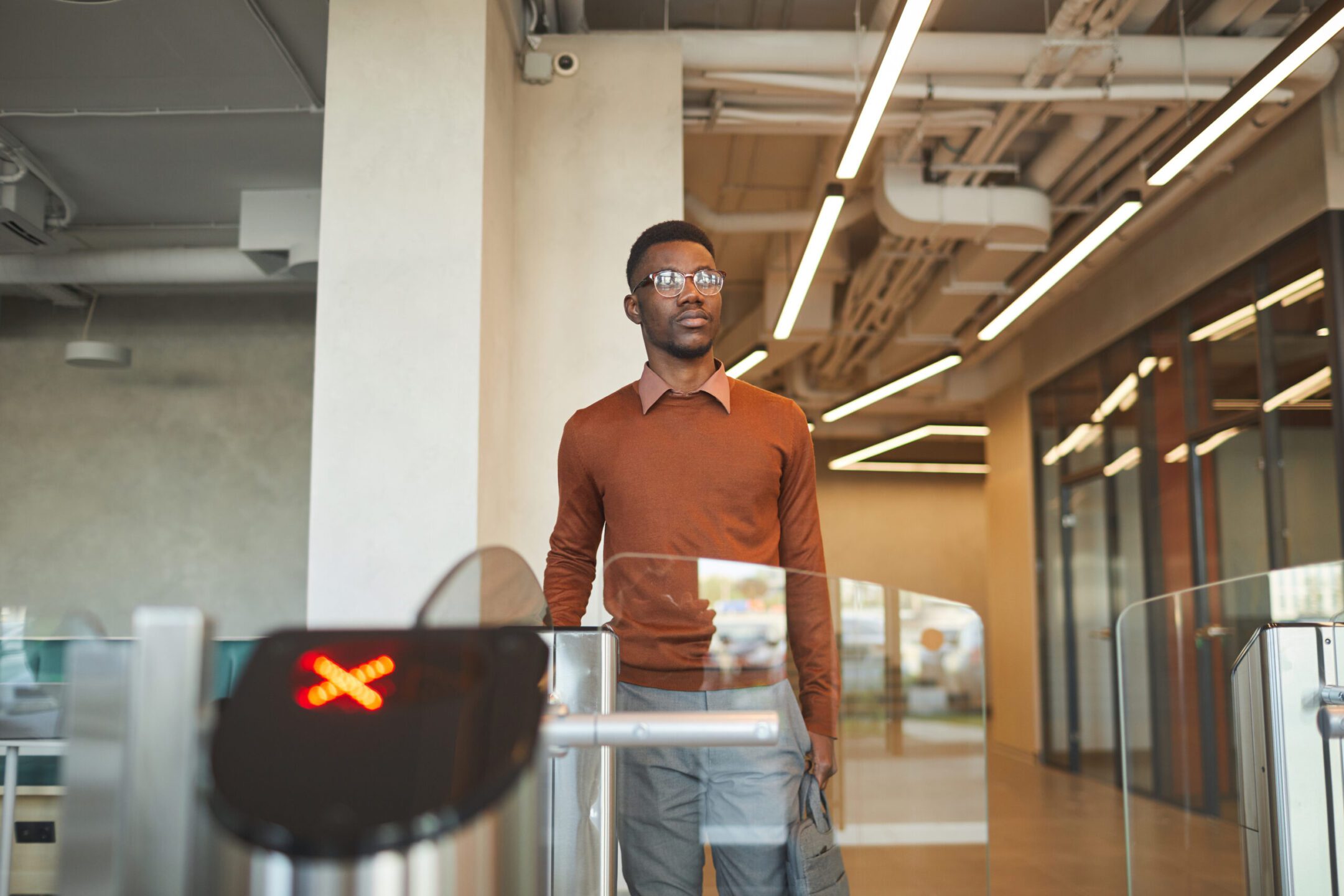Portrait of young man swiping ID car while passing automated gate to enter office building or college.